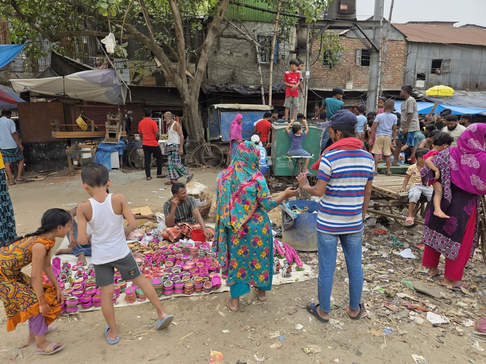 A busy community market in Bangladesh, with people gathering around colourful household goods